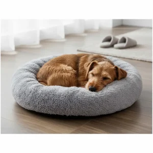 A small terrier curled up in a grey self-warming calming donut bed for winter on a wooden floor.