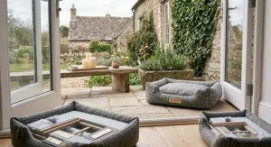A Scandi dog bed positioned on a stone patio outside a traditional British Cotswold stone cottage.