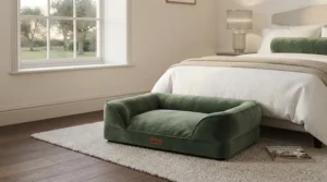 Sage green velvet sofa-style dog bed nestled beside a double bed in a cosy master bedroom.