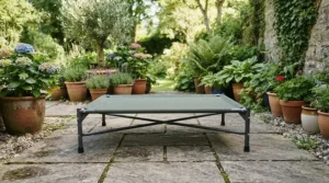 A portable elevated dog bed for hot weather placed on stone paving slabs in a modern courtyard.