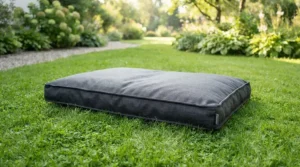 A waterproof garden dog bed sitting on a green lawn in a suburban back garden